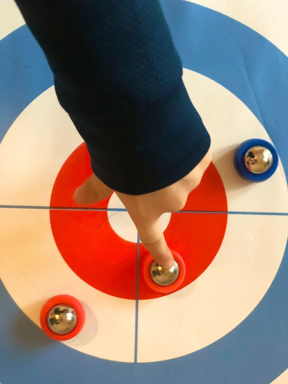 Doigt d'enfant poussant un palet sur une cible de curling de table