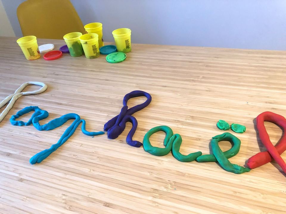 Lettres cursives formées en boudins de pâte à modeler de couleur sur une table