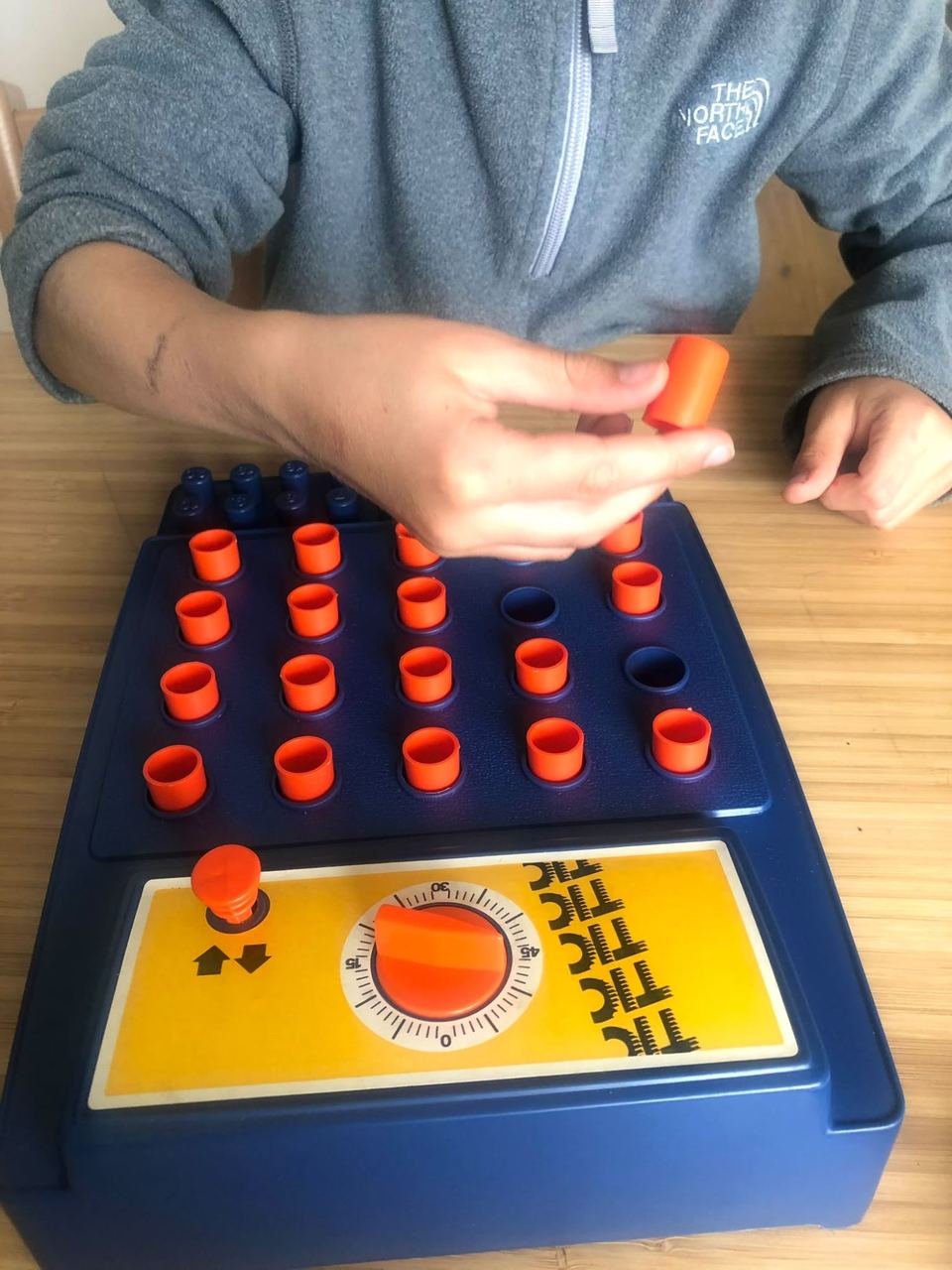 Enfant plaçant des pièces orange dans un jeu de rapidité à minuteur
